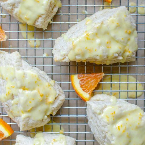 sourdough discard orange glazed scones on a wire rack with orange wedges