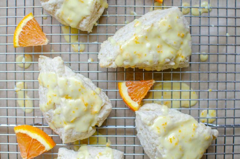 sourdough discard orange glazed scones on a wire rack with orange wedges