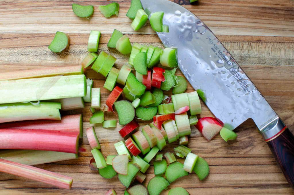 rhubarb stalks sliced on wooden cutting board with knife