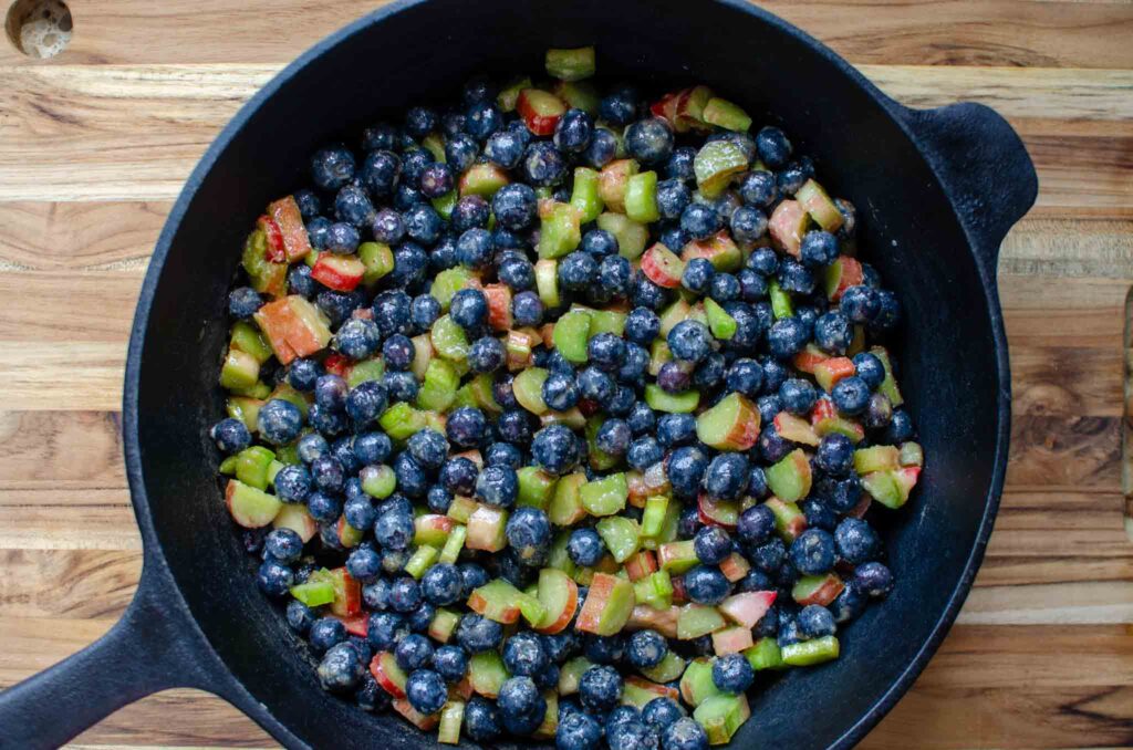 blueberry rhubarb crisp fruit mixture in large cast iron skillet