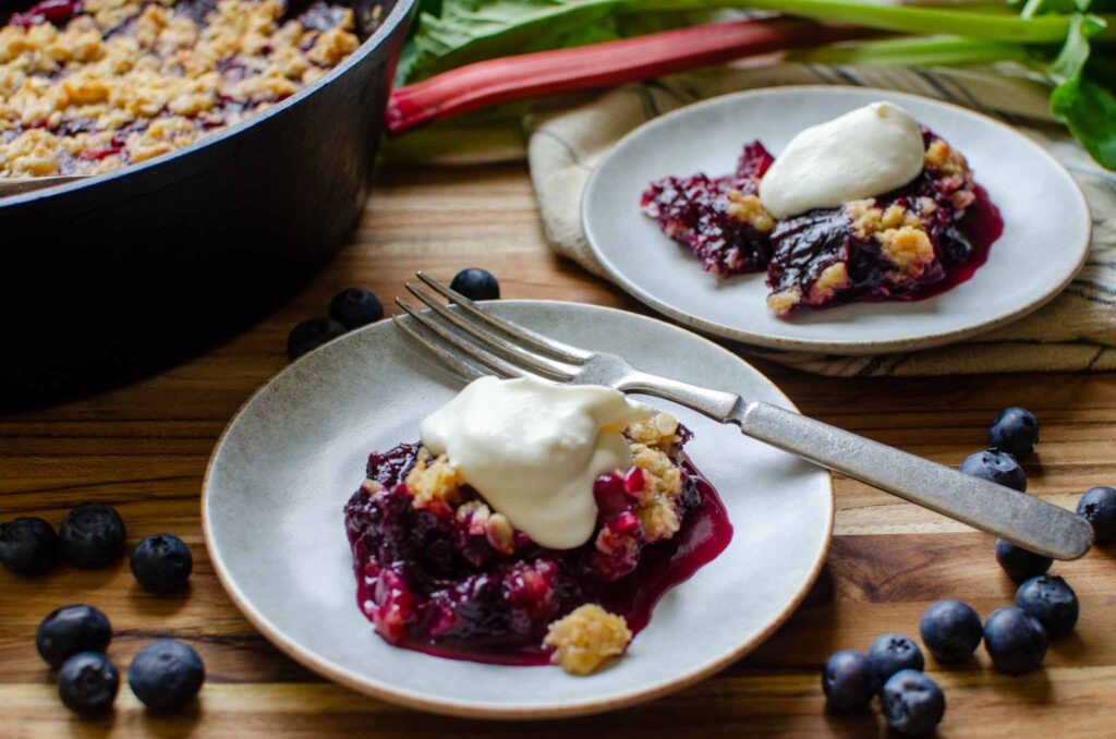 two plates of blueberry rhubarb crisp with whipped cream 