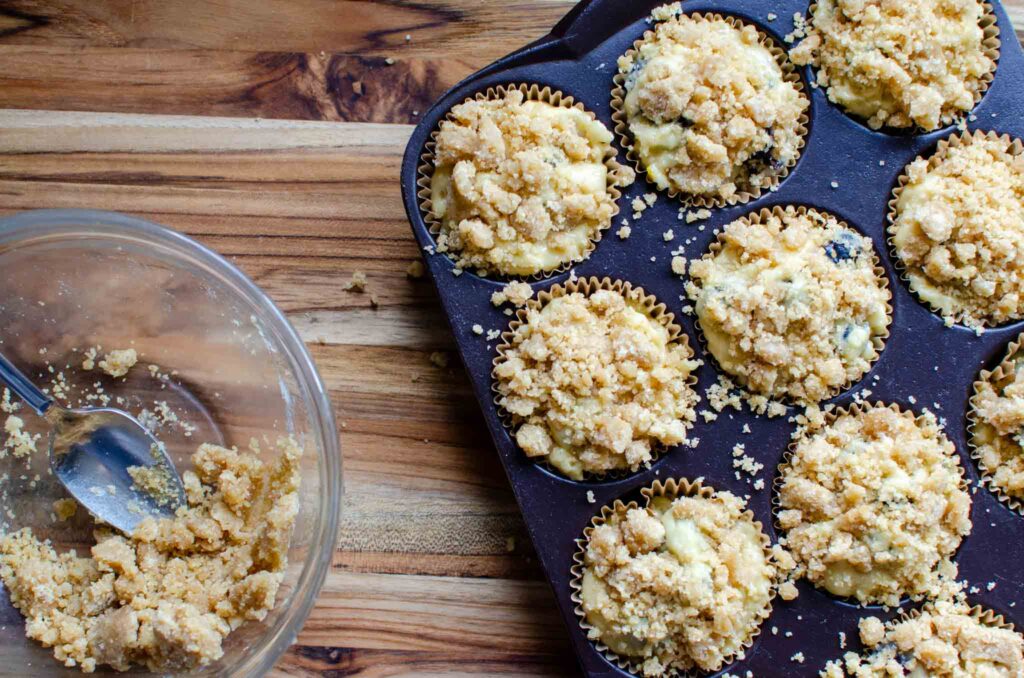 sourdough blueberry muffins batter with crumb mixture in muffin pan