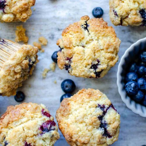 Multiple sourdough blueberry muffins with a bowl of blueberries