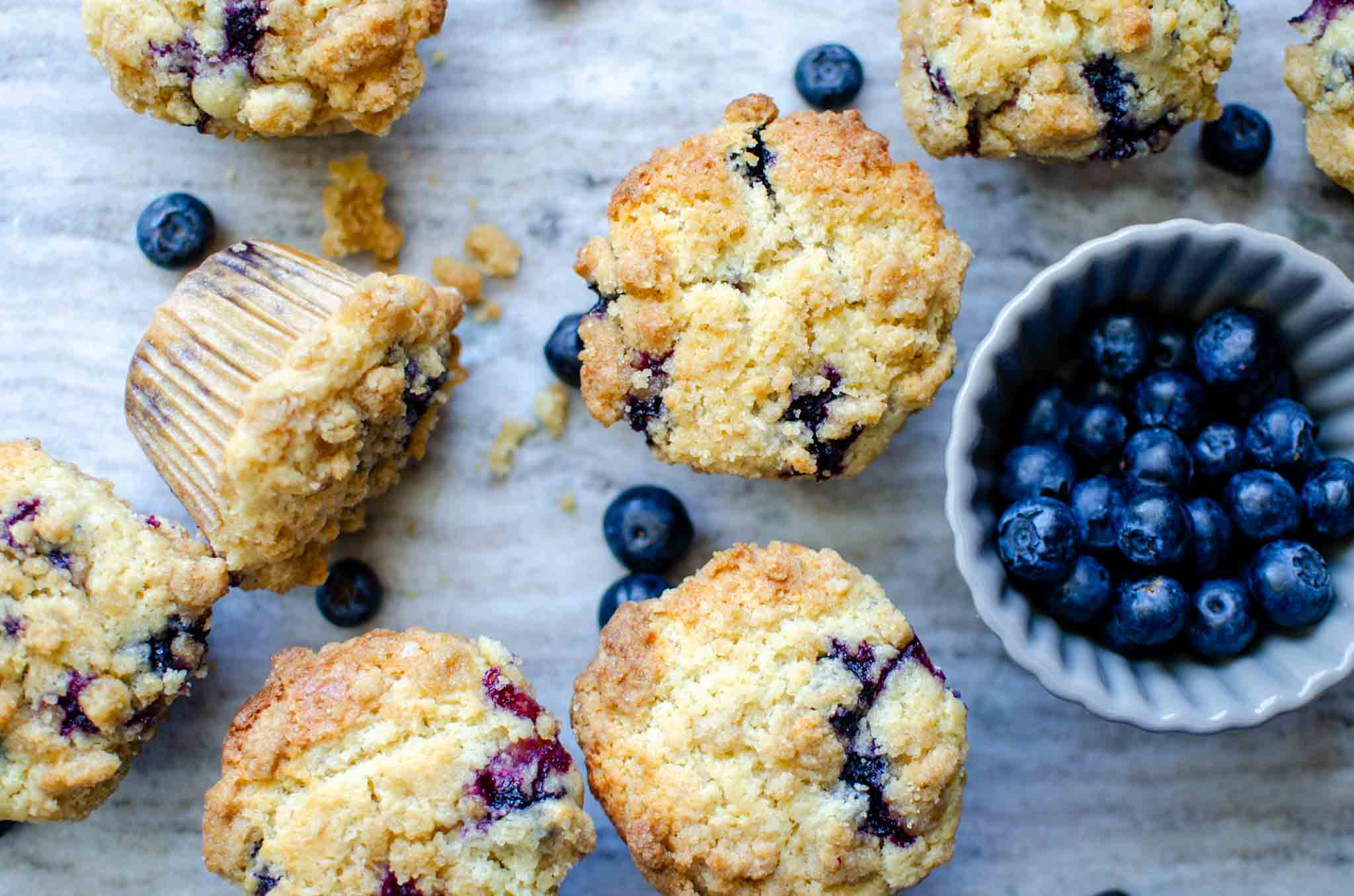 Multiple sourdough blueberry muffins with a bowl of blueberries