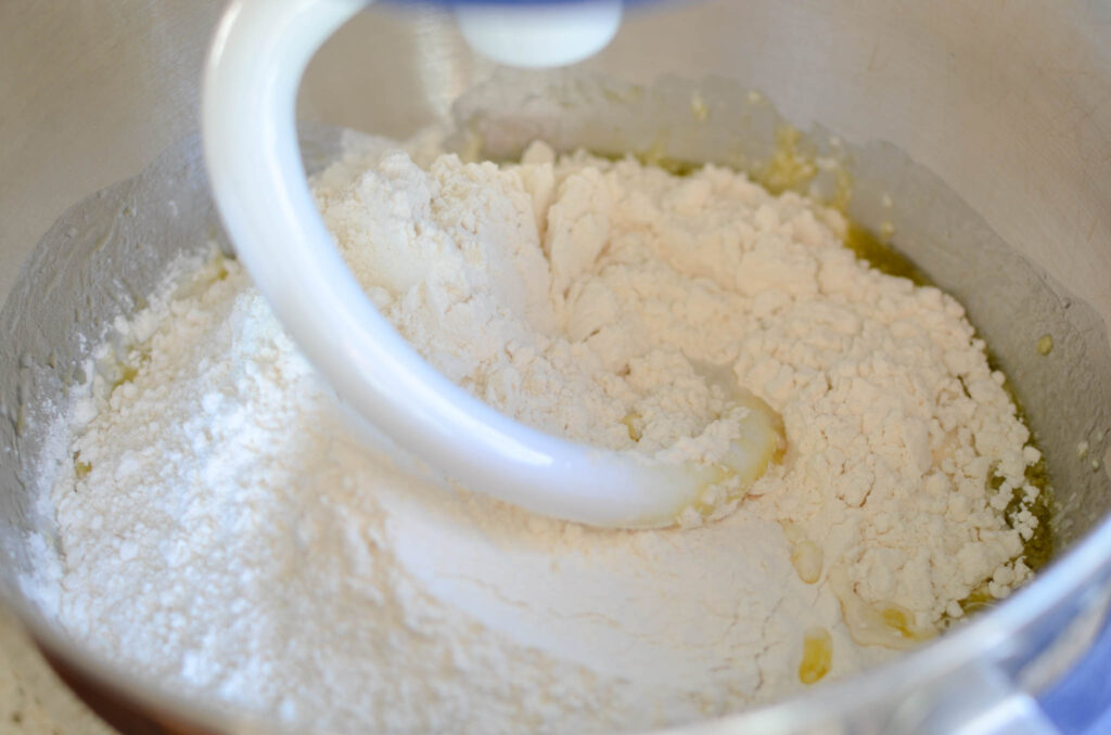 Sourdough pizza dough ingredients in mixer bowl with dough hook attachment