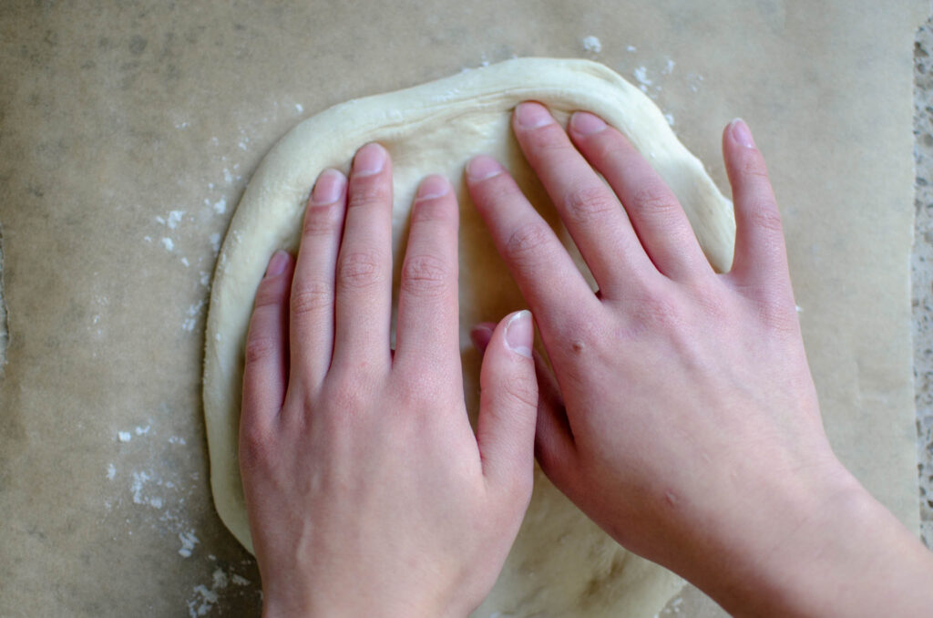 shaping the sourdough pizza crust with fingers 