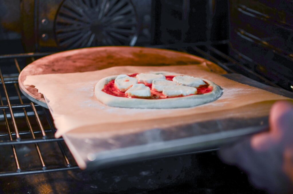 Sliding a sourdough pizza into the oven onto a pizza stone