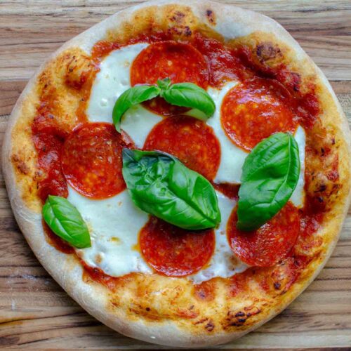 Sourdough pizza with mozzarella, pepperoni and fresh basil leaves