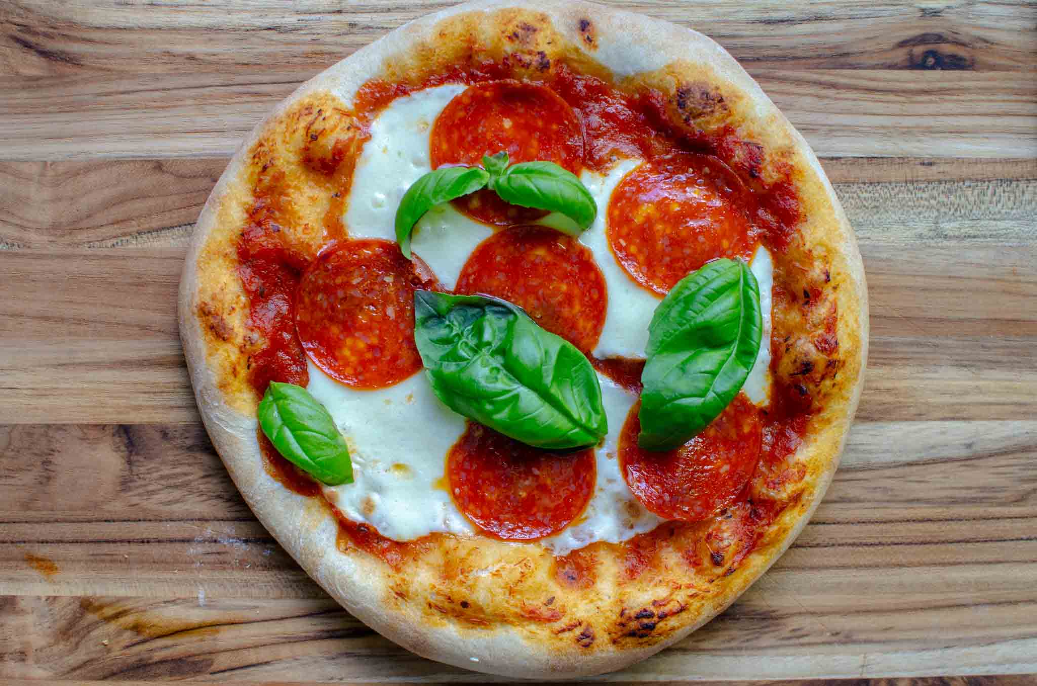 Sourdough pizza with mozzarella, pepperoni and fresh basil leaves