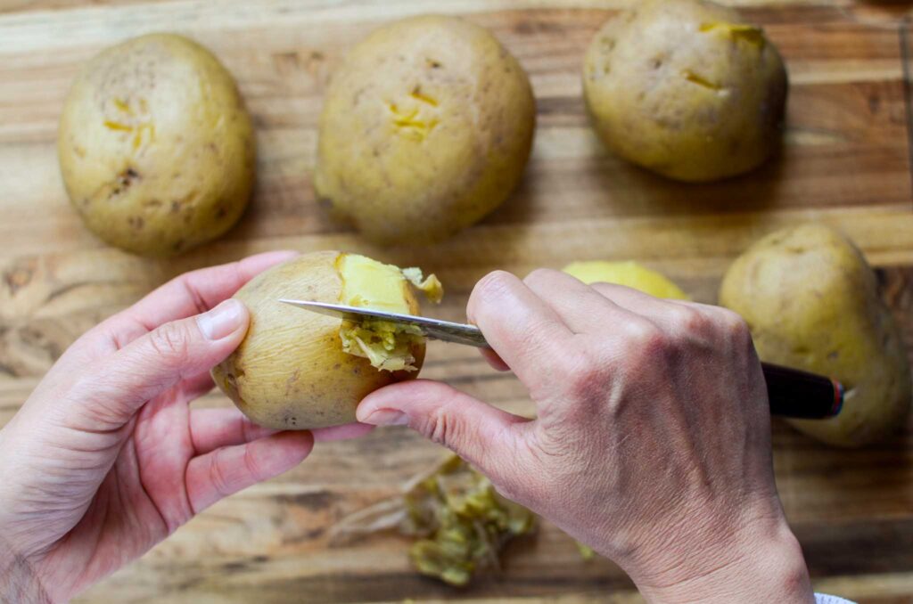 peeling thin skins of Yukon gold potatoes with small paring knife to make classic potato salad