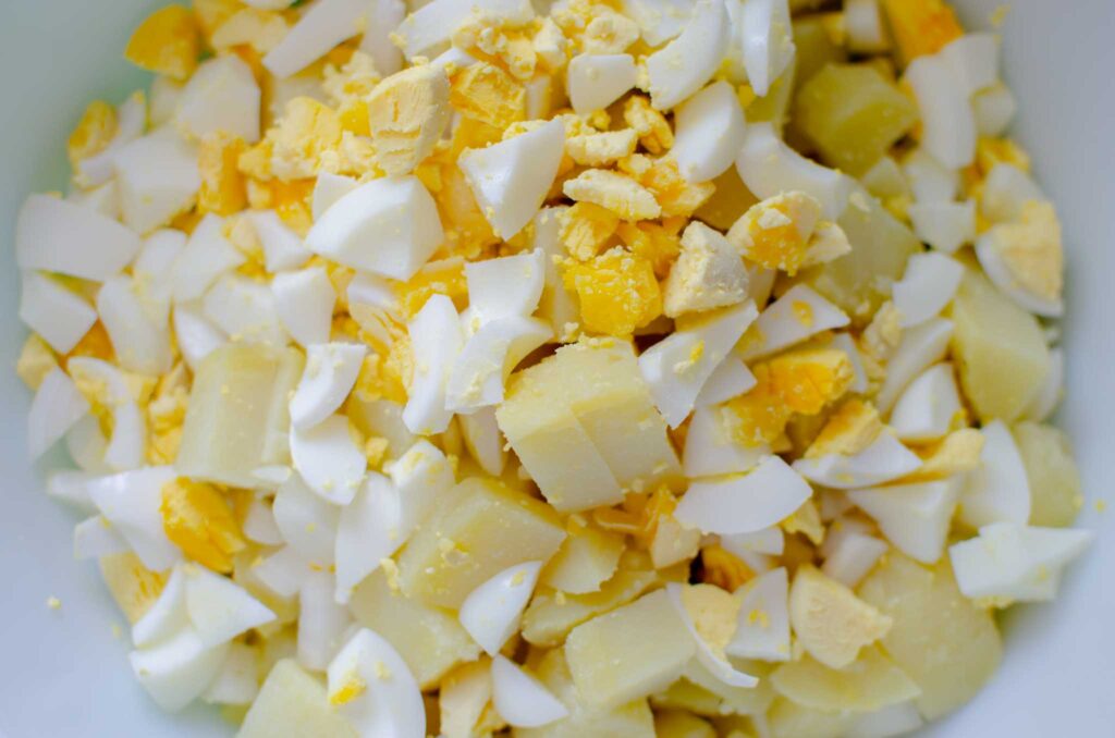 diced potatoes, hard-boiled eggs and onion for classic potato salad in large bowl