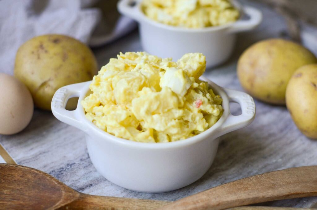 classic potato salad in two small dishes with potatoes all around