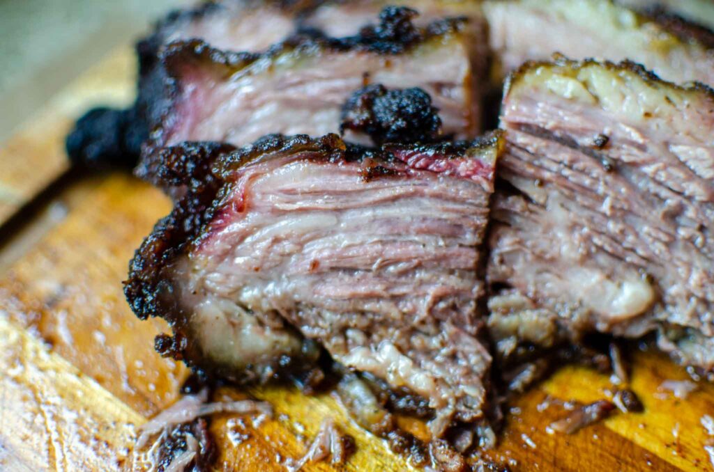 cut pieces of smoked beef brisket on wood cutting board