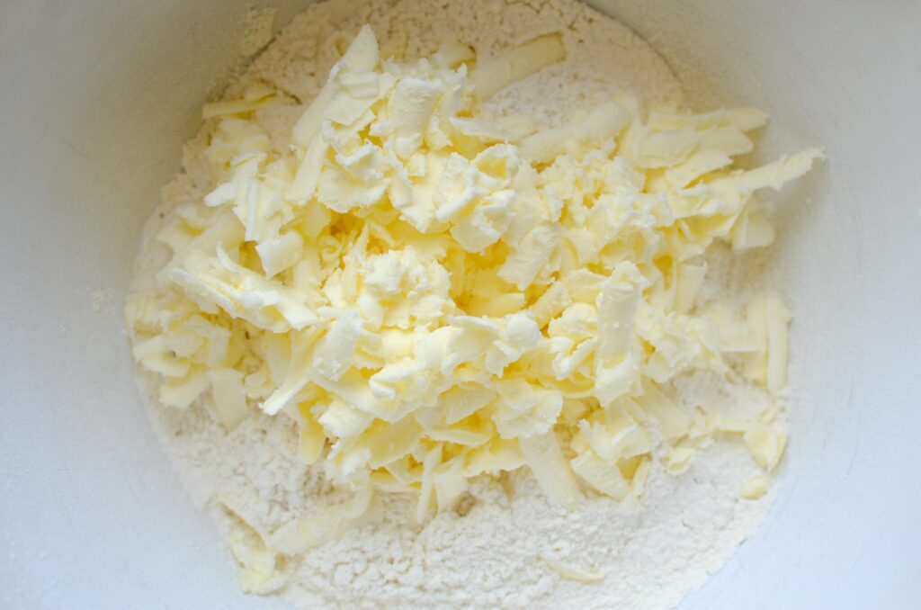 adding grated butter into flour mixture for Sourdough Discard Orange Scones 