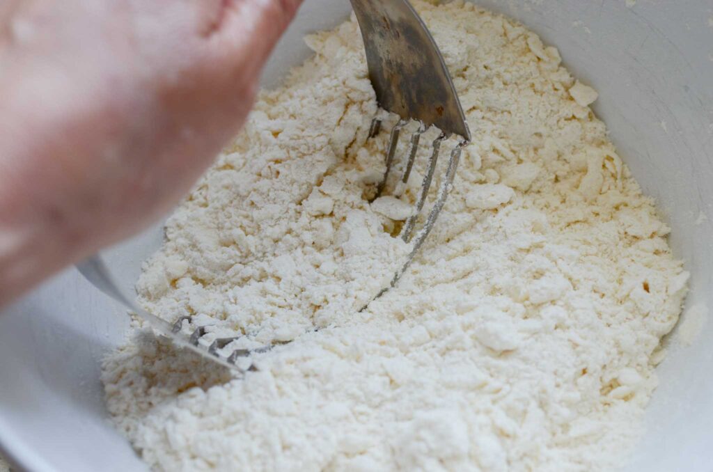 cutting butter into flour mixture with a pastry cutter for Easy Sourdough Discard Orange Scones Recipe