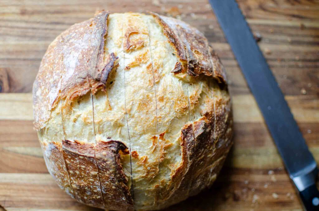 Cuts in a loaf of easy sourdough cheese and garlic pull-apart bread one way across