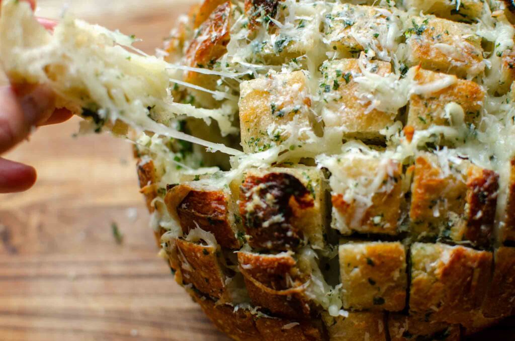 taking a piece off of Sourdough Cheese and Garlic Pull Apart Bread