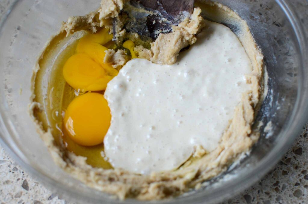 adding eggs and sourdough starter to butter mixture