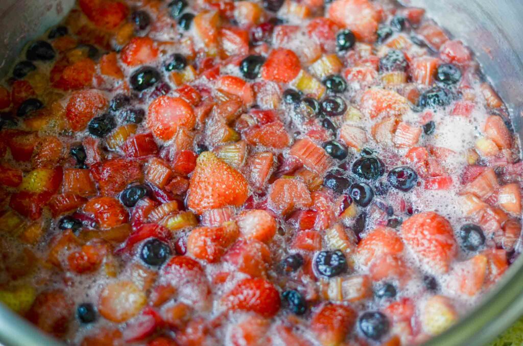 The fruit for mixed berry rhubarb jam simmering in a pot