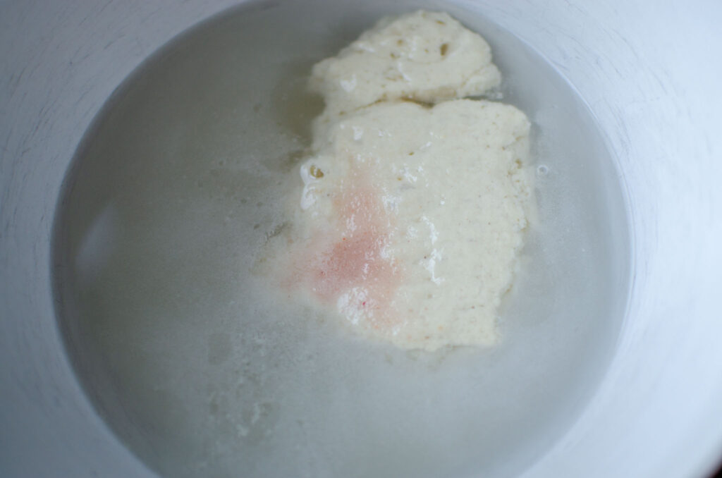 sourdough starter, salt, sugar and water in white bowl for sourdough focaccia bread dough