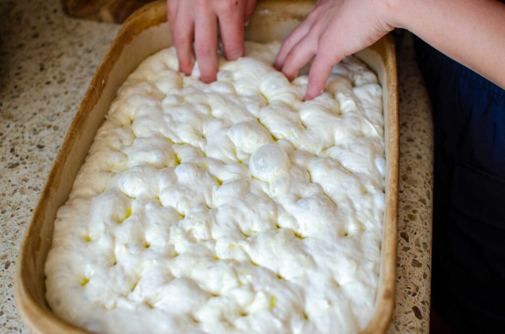 whole pan of dimpled sourdough cinnamon roll focaccia dough