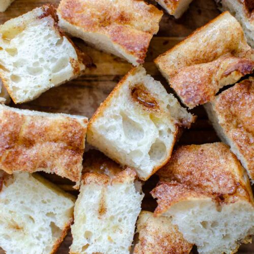 Pieces of sourdough cinnamon roll focaccia on wooden cutting board