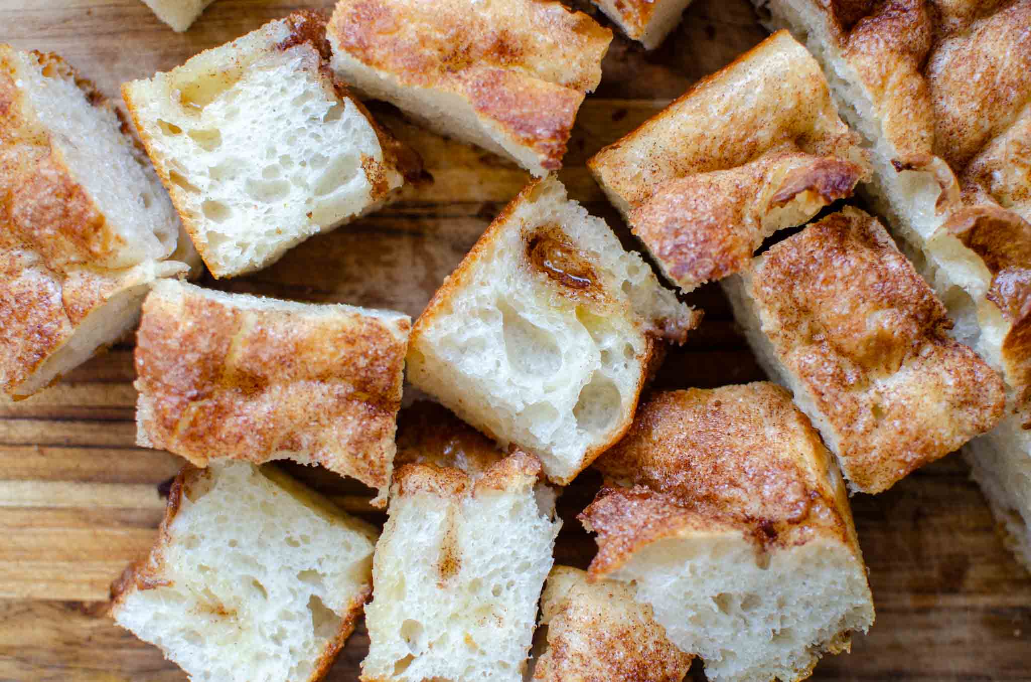 Pieces of sourdough cinnamon roll focaccia on wooden cutting board