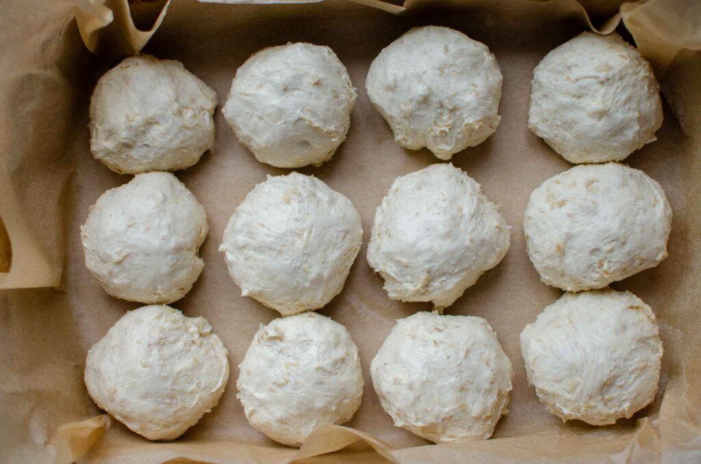 oatmeal dinner rolls dough balls in parchment lined pan before second rise