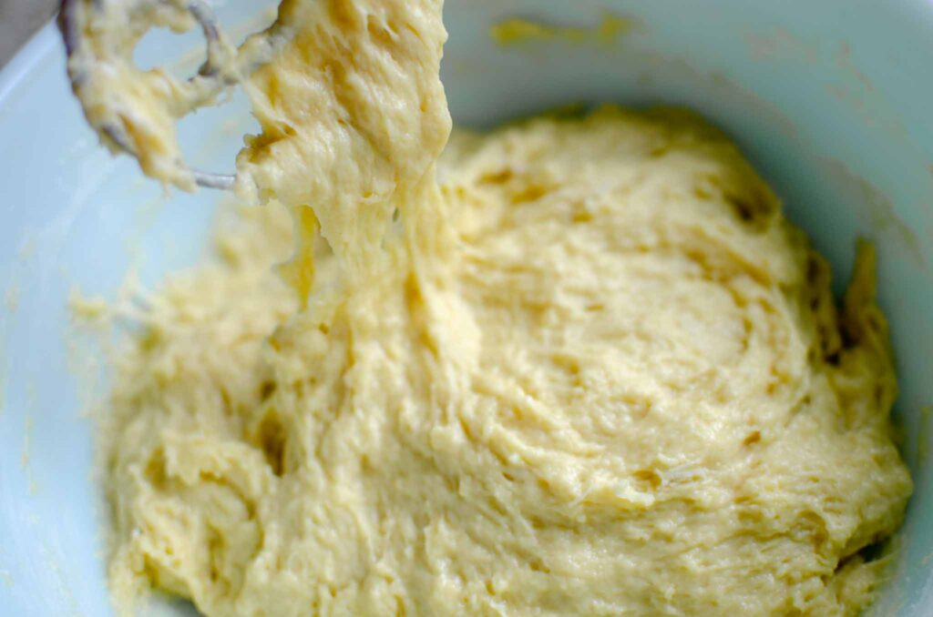 lifting the homemade sourdough cinnamon rolls dough with a Danish dough whisk to see how shaggy it is