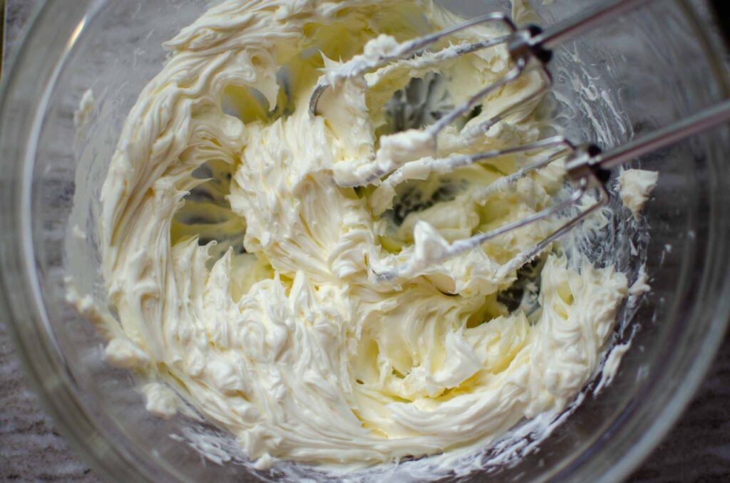 cream cheese creamed in a glass bowl with electric mixer