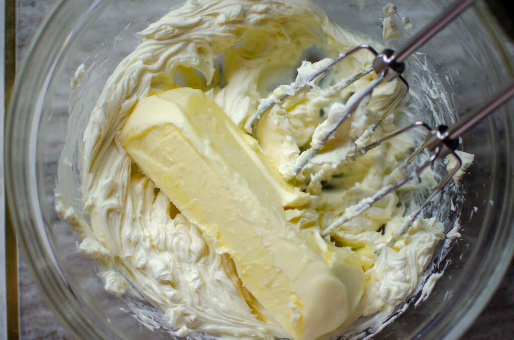 butter added to cream cheese in glass bowl