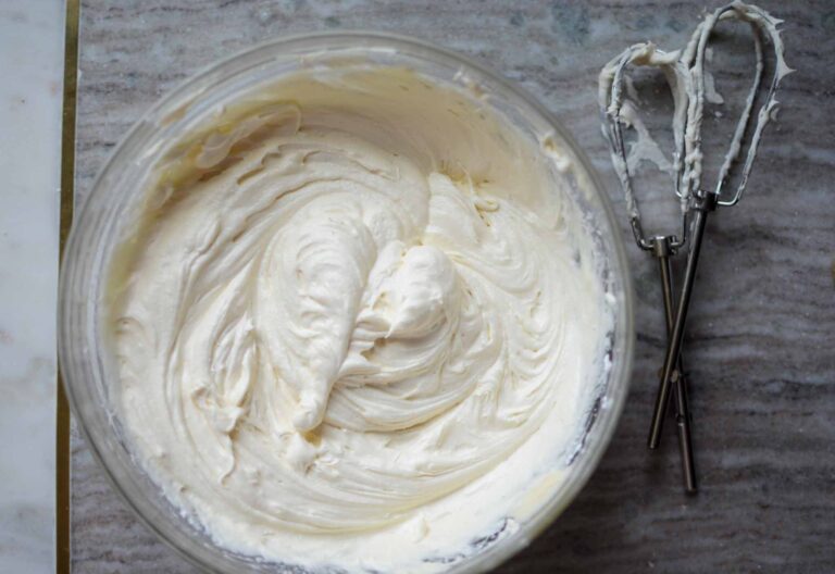 a bowl of homemade cream cheese frosting with beaters filled with frosting