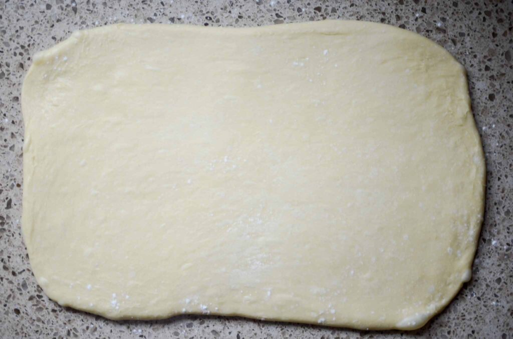 the cinnamon roll dough rolled out into a large rectangle