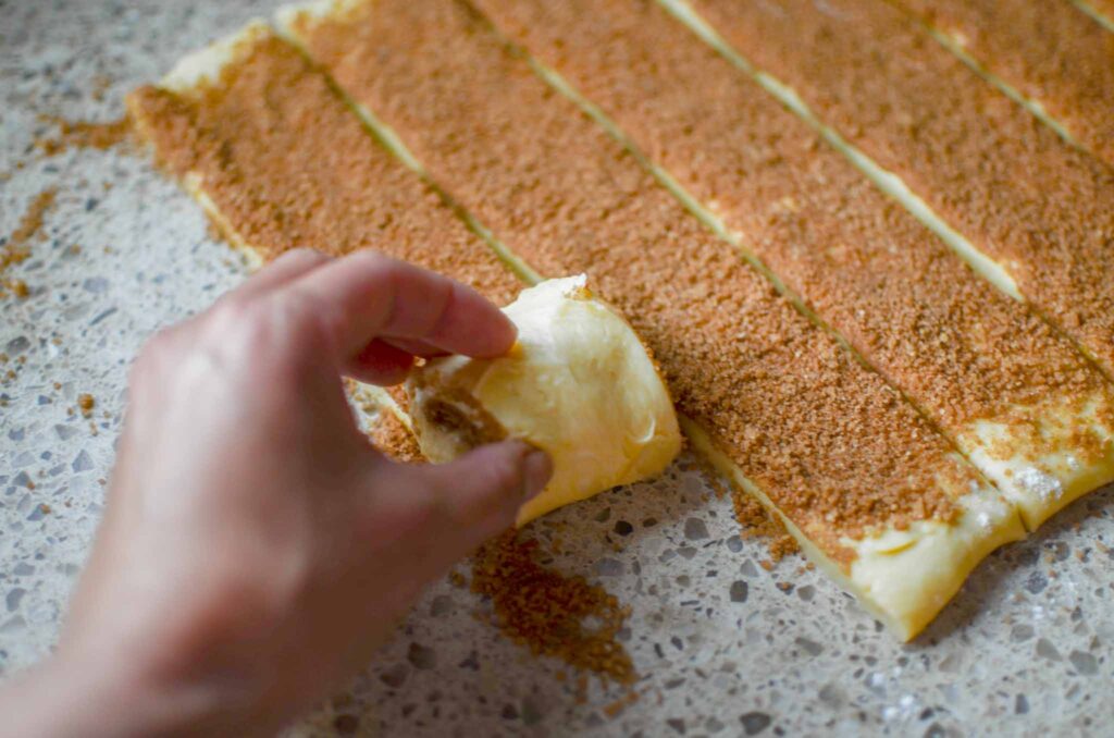 rolling each strip of cinnamon roll dough