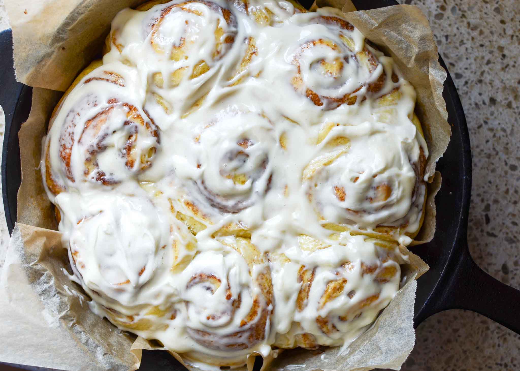 fluffy sourdough cinnamon rolls in cast iron round pan with parchment paper