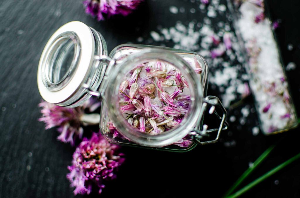 a small glass container with open lid of chive blossom salt