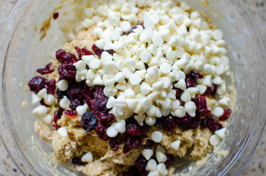 adding white chocolate chips and dried cranberries to sourdough cookie dough