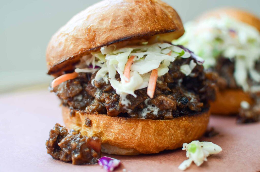 Leftover beef brisket sandwich topped with coleslaw and bun askew on top