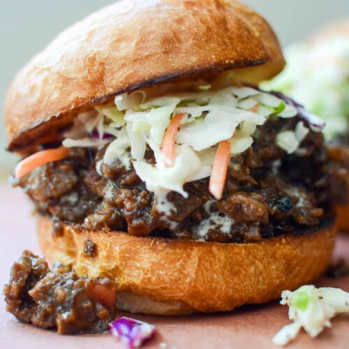 Leftover beef brisket sandwich topped with coleslaw and bun askew on top