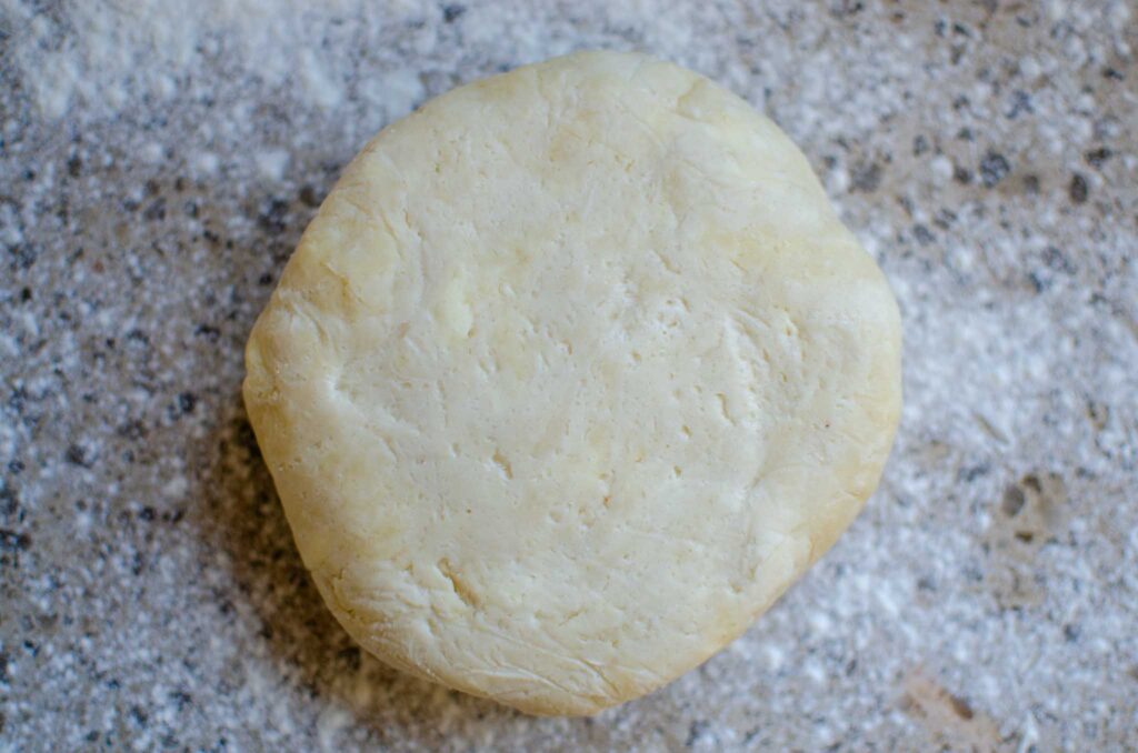 Sourdough pie crust disc on floured surface