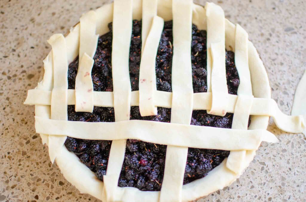 Laying perpendicular strips of pie crust for mulberry pie 