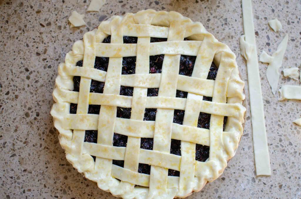 unbaked mulberry pie with lattice top with egg wash and turbinado sugar