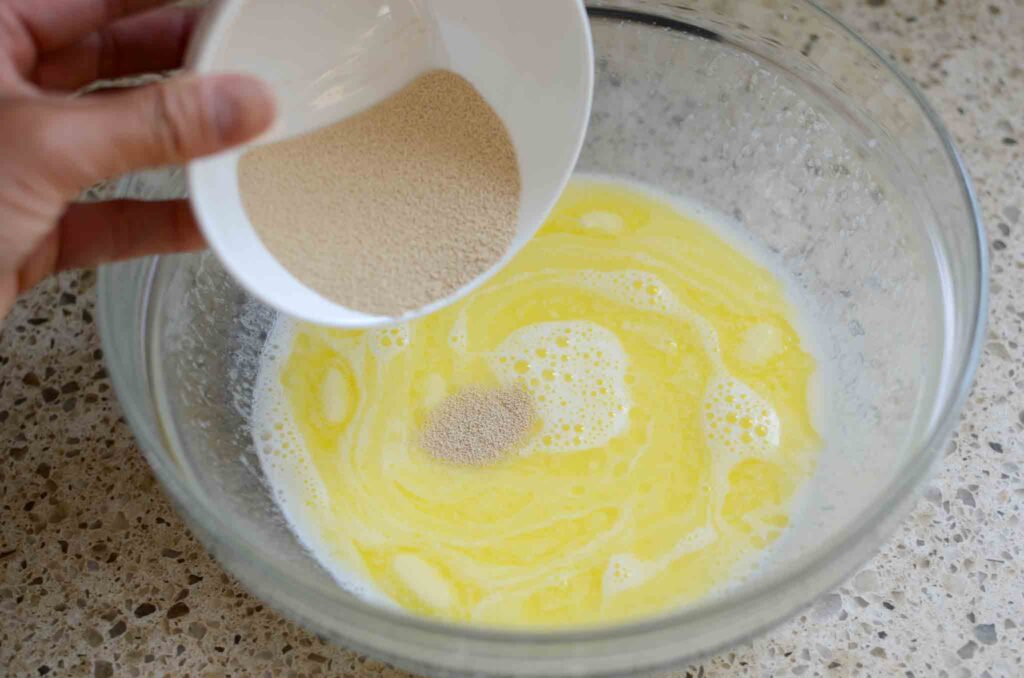 pouring instant yeast to warm milk and butter mixture