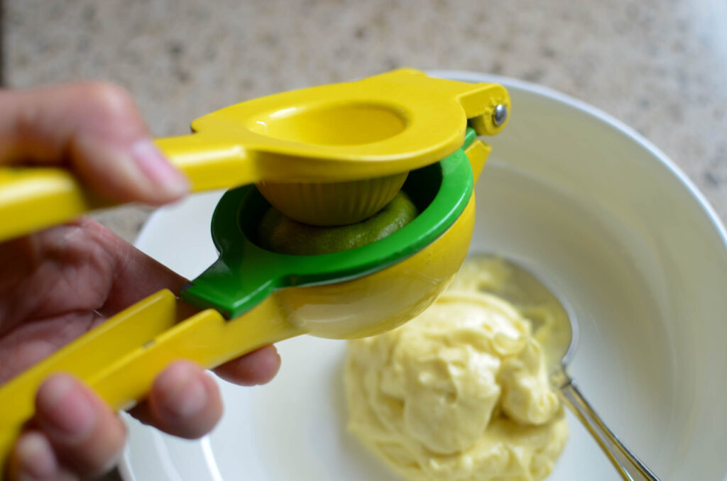 Squeezing lime juice over a bowl of mayo