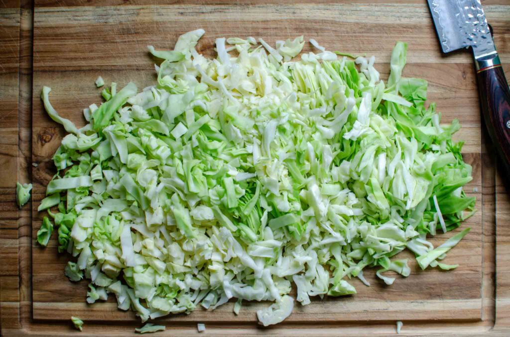 shredded cabbage on wooden cutting board