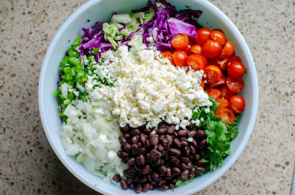 All of the ingredients from roasted Mexican street corn slaw salad in a large bowl