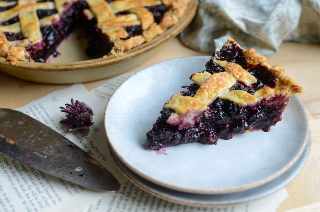 a slice of classic mulberry pie on stacked plates