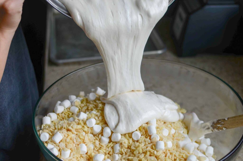 pouring melted marshmallows over rice krispies cereal