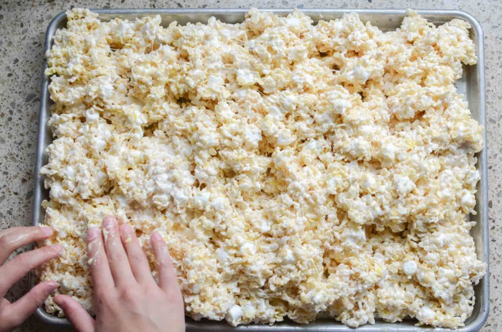 spreading rice krispies treat mixture into large pan