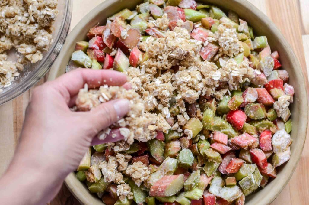 adding crisp mixture over rhubarb in baking dish